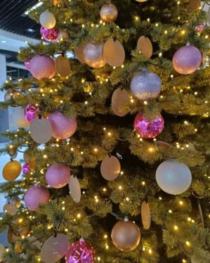 Stort juletræ med varm hvid LED lyskæde med sort ledning og lyserøde julekugler.