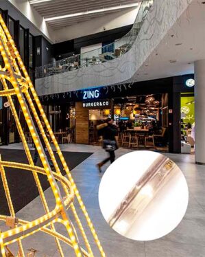 Lysende juledekoration i et shoppingcenter med varme hvide LED-lys. Moderne indkøbsområde med restaurant i baggrunden. Indsat zoom viser detalje af et ropelight LED-lysrør for kvalitet og design.