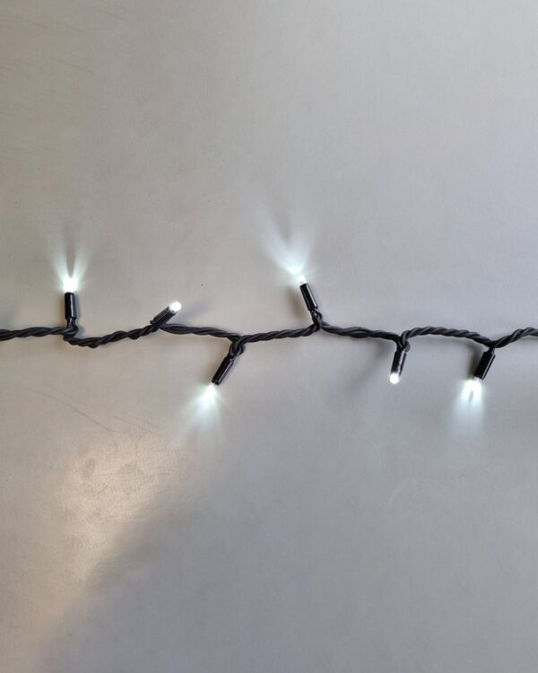Lyskæde med kold hvid LED-lys på sort ledning. Viser klart, neutralt skær mod lys baggrund og egner sig til moderne juleudsmykning.
