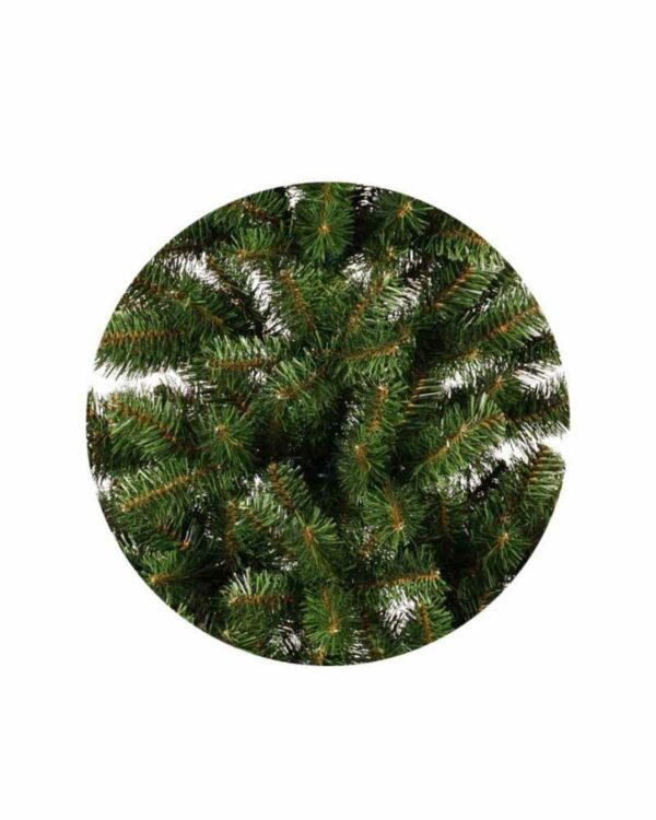 Nærbillede af kunstigt juletræs grangrene med tætte grønne nåle og brunlige kviste, vist i cirkulært udsnit mod hvid baggrund.