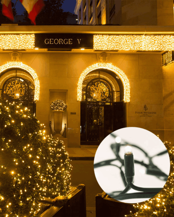 Hotel George V's indgang stråler med buede porte og træer dækket af lys - luksus og elegance i hjertet af natten.