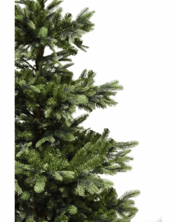 Meget naturtro kunstigt juletræ set helt tæt på. Man ser næsten halvdelen af træet og fornemmer dybden og effekten af at grenene er lavet af PE og PVC.