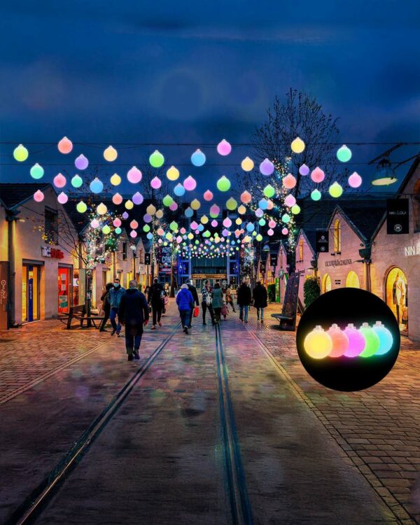 Farverige LED-kugler hænger på stribe over en gågade og skaber en livlig, festlig atmosfære. Perfekt til sæsonudsmykning i bymidter, shoppingområder og events.