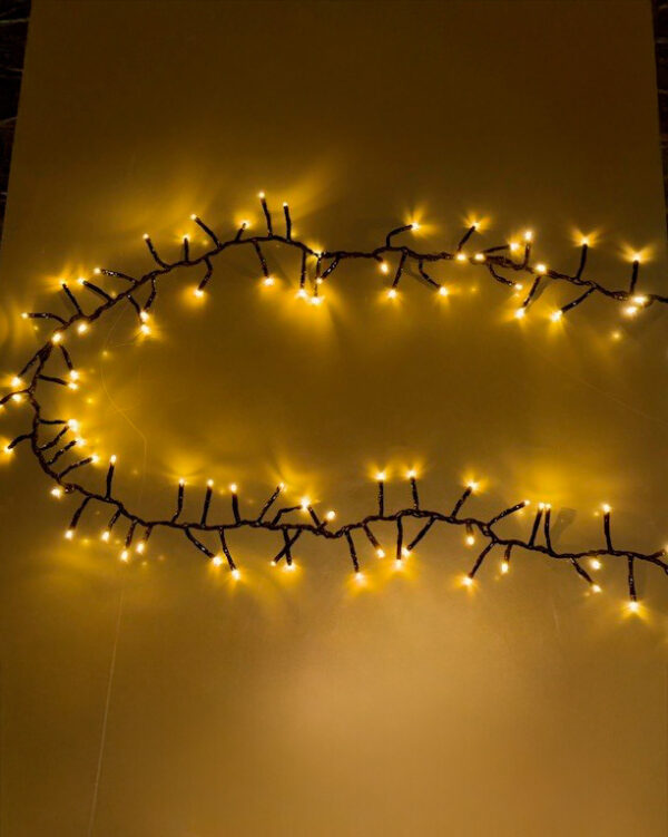 Klyngelyskæde med sort kabel og varm hvide LED-pærer, arrangeret i tæt mønster. Lyser smukt op og skaber en dekorativ stemning til både indendørs og udendørs brug.