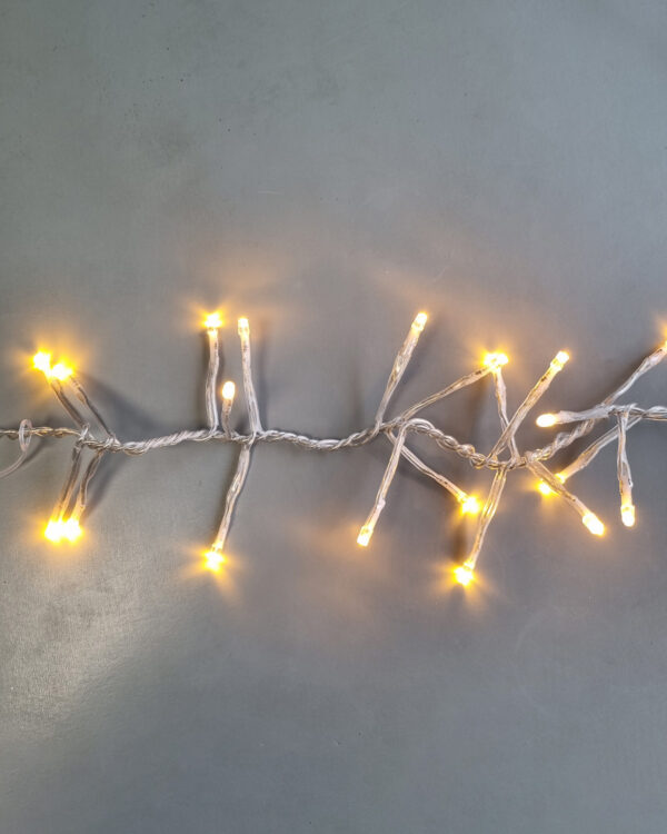 Klyngelyskæde med varm hvid LED-belysning og transparent kabel, der giver et blødt og hyggeligt lys - ideel til juletræer, facader og indendørs dekoration.