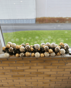 Færdigpyntet granguirlande med perlemor, champagne- og sølvkugler samt varm hvid LED-belysning. Perfekt til vindueskarme, receptioner eller festlige juleudstillinger.