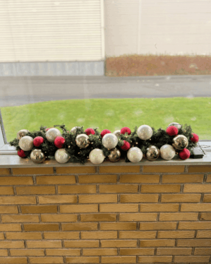 Pyntet granguirlande med røde, perlefarvede og champagnefarvede kugler samt små LED-lys. En elegant og moderne juledekoration, der skaber lys, varme og klassisk stemning.