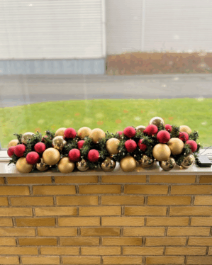 Færdigpyntet granguirlande med røde og champagne kugler samt varm hvide LED-lys. Skaber en klassisk, elegant og festlig julestemning i vindueskarmen.