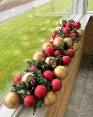 Elegant granguirlande pyntet med røde og champagne kugler samt varm hvide LED-lys. Perfekt til vindueskarm eller butik for et klassisk juleudtryk.