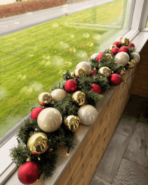 Elegant granguirlande pyntet med røde, perlemor og champagne kugler samt varm hvide LED-lys. Perfekt til vindueskarm for et klassisk juleudtryk.