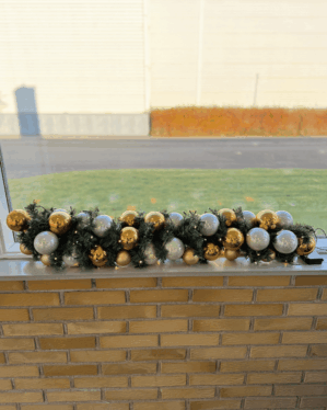 Juleguirlande med grønne grene, guldfarvede og perlemor kugler samt varm LED-belysning. Elegant dekoration til vindueskarm, der skaber en eksklusiv og festlig stemning.