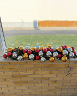 Festlig juleguirlande med røde, sølv- og guldfarvede kugler samt varm LED-belysning. Perfekt som vindues- eller butiksudsmykning med klassisk julefarvebalance.