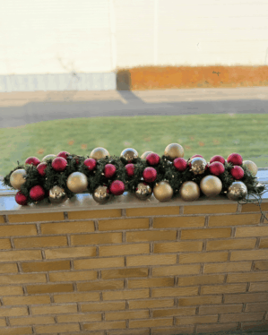 Færdigpyntet juleguirlande med røde, guld- og champagnefarvede kugler samt LED-lys. Perfekt til vindueskarme, receptioner og indgangspartier med klassisk julestemning.