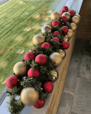 Elegant juleguirlande med røde, guld- og champagnekugler samt varm LED-belysning. Perfekt som vinduespynt eller borddekoration med klassisk og stemningsfuld juleudstråling.
