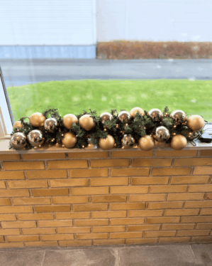Juleguirlande med sølv og champagne julekugler og varm hvid LED-belysning placeret i vindueskarm. Skaber et eksklusivt og elegant udtryk med klassisk julestemning.