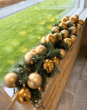 Granguirlande pyntet med guld- og champagnefarvede kugler og varm hvid LED-lyskæde. Skaber en eksklusiv julestemning i vindueskarm, butik eller reception.