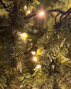 Nærbillede af kunstigt juletræ  fra Exclusive-serien med realistiske grønne grene og varm hvid LED-lyskæde, hvor lyspunkter skaber dybde, glød og stemningsfuldt juleudtryk.