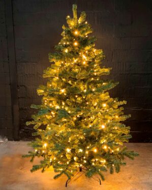 Kunstigt juletræ fra Exclusive-serien med tætgrønne grene og integreret varm hvid Jada light PRO LED-lyskæde, opstillet på stabil fod mod mørk baggrund og skaber et klassisk, stemningsfuldt juleudtryk.