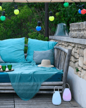 Multifarvet lyskæde med store pærer i sommermiljø udendørs