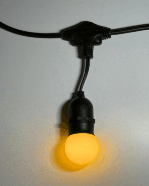Nærbillede af sort party-lyskæde med varm gul LED-pære, der giver et blødt og indbydende lys, velegnet til både indendørs og udendørs dekorativ belysning året rundt.